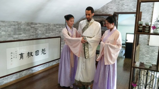 El Amine Cherrat from Ecole Polytechinique, dressed in hanfu, learns the correct way to hold his hands with the help of two students from Nanjing Agricultural University, before practicing how to make tea, on Sunday. Photo provided to chinadaily.com.cn El Amine Cherrat from Ecole Polytechinique, dressed in hanfu, learns the correct way to hold his hands with the help of two students from Nanjing Agricultural University, before practicing how to make tea, on Sunday. Photo provided to chinadaily.com.cn