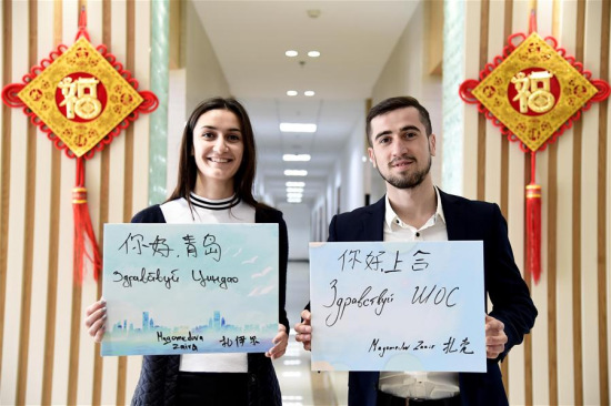 Russian student Zakir (R) and his sister Zaira, both studying in China University of Petroleum, display boards with Chinese and Russian handwritings of