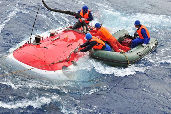 Workers try to put cables onto Jiaolong, China's first manned deep-sea submersible, after the completion of a research program.(Photo/Xinhua) Workers try to put cables onto Jiaolong, China's first manned deep-sea submersible, after the completion of a research program.(Photo/Xinhua)