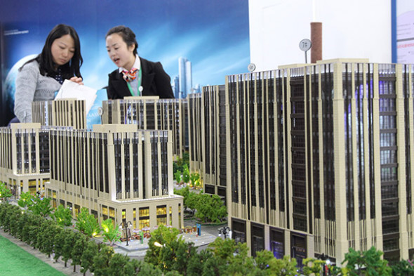 Visitors look at a model of a housing project at a real estate exhibition in Beijing. (Photo provided to China Daily)