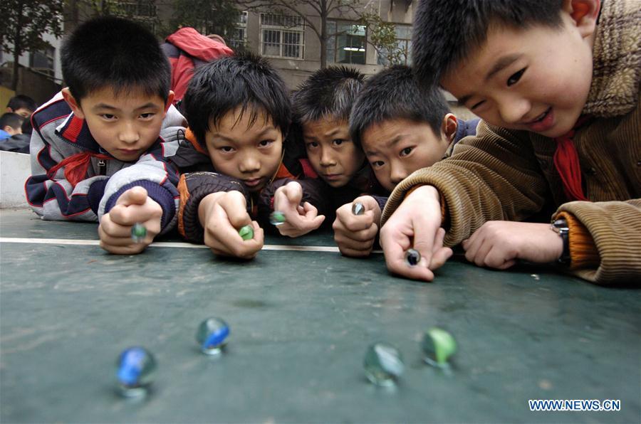 In this file photo taken on Dec. 18, 2007, students play a classic marble game at Changjianglu Primary School in Nanjing, east China\'s Jiangsu Province. As China celebrates the International Children\'s Day, there arises the occasion for grown-ups to think back over the joys of childhood. With the evolution of technology and lifestyle, children are exposed to a wider range of entertainment. Nevertheless, joy would remain a childhood motif no matter how its forms change with time. (Xinhua/Sun Can)