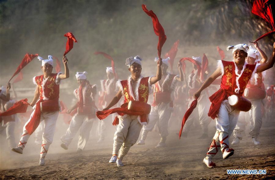 Villagers perform Ansai waist drums for tourists at Fengjiaying Village in Ansai District of Yan\'an City, northwest China\'s Shaanxi Province, May 30, 2018. It is believed that the Ansai Waist Drum dance is a unique, large-scale folk dance with a history of more than 3,000 years. Like a hurricane sweeping across the yellow earth, the dance displays the unsophisticated and wild character of peasant life on the Loess Plateau, revealing its unique artistic charm. (Xinhua/Tao Ming)