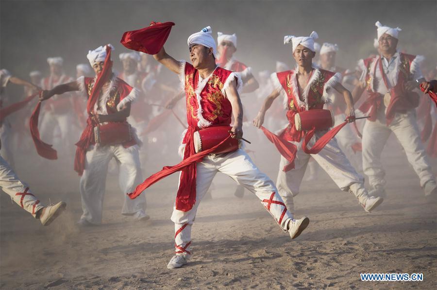 Villagers perform Ansai waist drums for tourists at Fengjiaying Village in Ansai District of Yan\'an City, northwest China\'s Shaanxi Province, May 30, 2018. It is believed that the Ansai Waist Drum dance is a unique, large-scale folk dance with a history of more than 3,000 years. Like a hurricane sweeping across the yellow earth, the dance displays the unsophisticated and wild character of peasant life on the Loess Plateau, revealing its unique artistic charm. (Xinhua/Tao Ming)