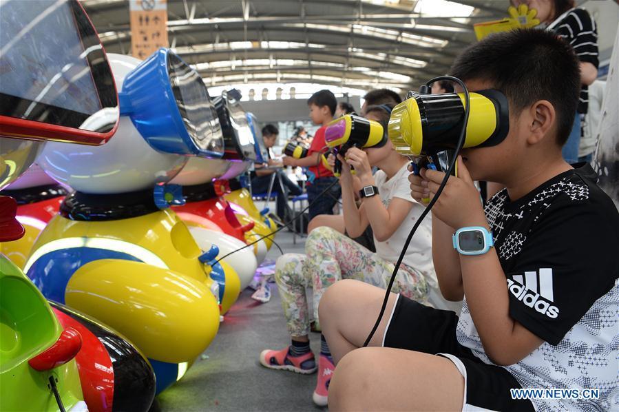 In this file photo taken on May 28, 2017, children wear VR (virtual reality) equipment during a technology event in Xi\'an, northwest China\'s Shaanxi Province. As China celebrates the International Children\'s Day, there arises the occasion for grown-ups to think back over the joys of childhood. With the evolution of technology and lifestyle, children are exposed to a wider range of entertainment. Nevertheless, joy would remain a childhood motif no matter how its forms change with time. (Xinhua/Liu Xiao)