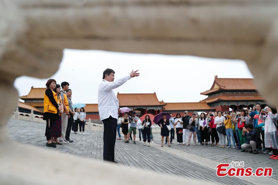 Shan Jixiang, the curator of the Palace Museum, meets with visitors to a restoration \'hospital\' in the Palace Museum in Beijing, June 9, 2018. As part of ongoing activities held for China\'s Cultural and Natural Heritage Day, the first batch of 40 people watched \'doctors\' repairing pieces from some of the museum\'s collections, including pieces of calligraphy, paintings, bronzeware and clocks, under the guidance of volunteers. Established in December 2016, the restoration hospital is located in the west of the Palace Museum. The facility covers 13,000 square meters and has the nation\'s most-advanced restoration studios. (Photo: China News Service/Liu Guanguan)