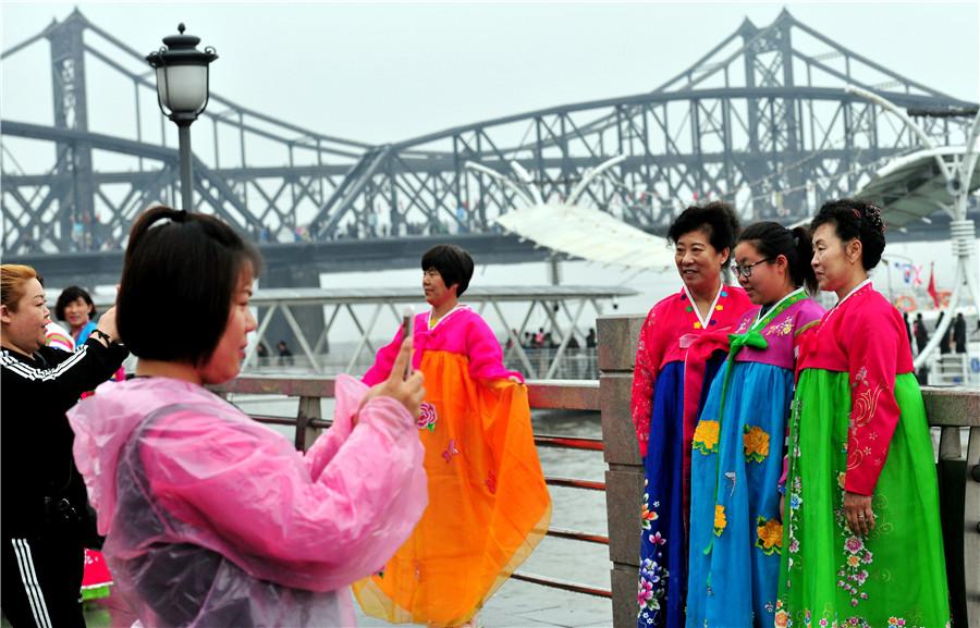 Tourists dressed in Korean ethnic garb pose in front of the Yalu River in Dandong, Liaoning province, on May 1. (YU HAIYANG/FOR CHINA DAILY)
Kim Jong-un\'s visit reaffirmed DPRK\'s long-standing friendship with China
On March 25, Zhou Linqing rode the train from Dandong, Liaoning province, to Pyongyang, capital of the Democratic People\'s Republic of Korea. He was going to meet with business partners from the country, which is clearly visible across the Yalu River, the waterway that flows through the northeastern city.
The journey, which takes about seven hours, is usually smooth and untroubled, but on this occasion Zhou\'s train stopped suddenly a few hours after leaving Dandong. The native of the border city recalled that his train remained stationary for a long time before moving on, but no reason was given.
Three days later, he learned that the train had been stopped to make way for a special train carrying Kim Jong-un, who was heading to Beijing for talks with President Xi Jinping as part of the DPRK top leader\'s first overseas trip since assuming office in December 2011. He also visited Dalian in Liaoning in May.
Kim is now on his third overseas visit, having arrived in Singapore on Sunday ahead of a summit meeting with United States President Donald Trump.