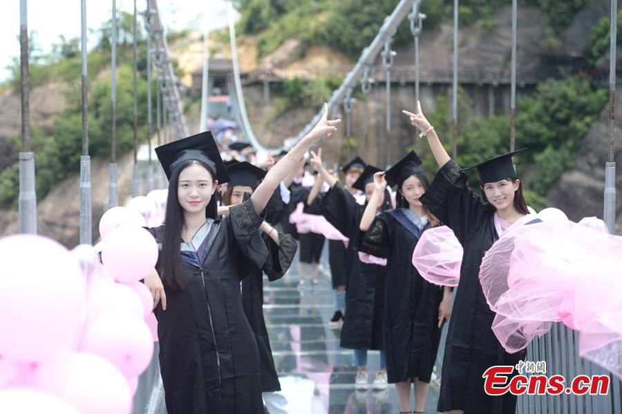 Students take creative graduation photos on a glass-bottom bridge in the Shiniuzhai National Geological Park in Pingjiang County, Central China\'s Hunan Province, June 27, 2018. The transparent bridge is suspended between two cliffs, 180 meters above ground. (Photo: China News Service/Yang Huafeng)
