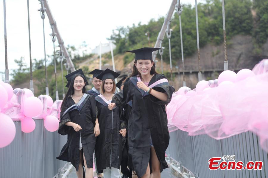 Students take creative graduation photos on a glass-bottom bridge in the Shiniuzhai National Geological Park in Pingjiang County, Central China\'s Hunan Province, June 27, 2018. The transparent bridge is suspended between two cliffs, 180 meters above ground. (Photo: China News Service/Yang Huafeng)