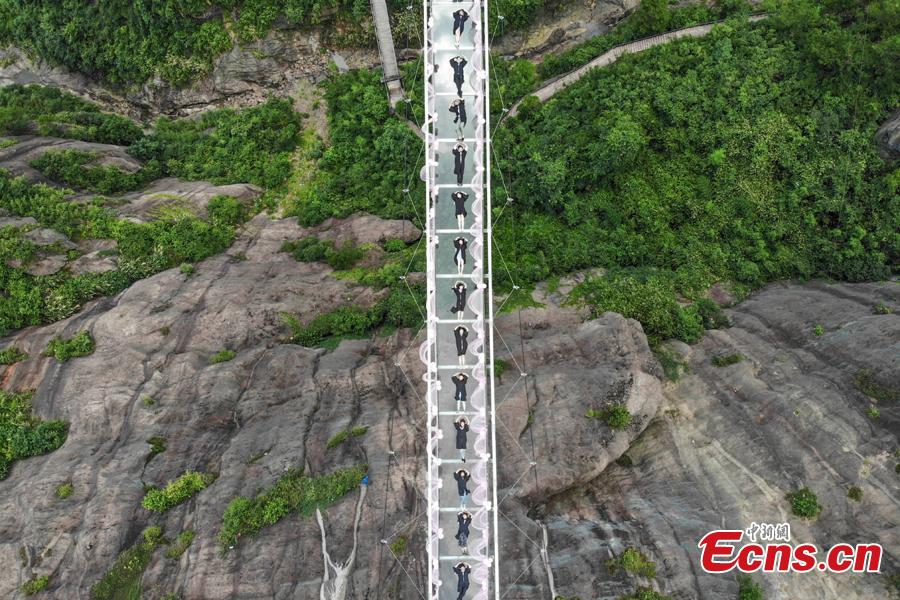 Students take creative graduation photos on a glass-bottom bridge in the Shiniuzhai National Geological Park in Pingjiang County, Central China\'s Hunan Province, June 27, 2018. The transparent bridge is suspended between two cliffs, 180 meters above ground. (Photo: China News Service/Yang Huafeng)