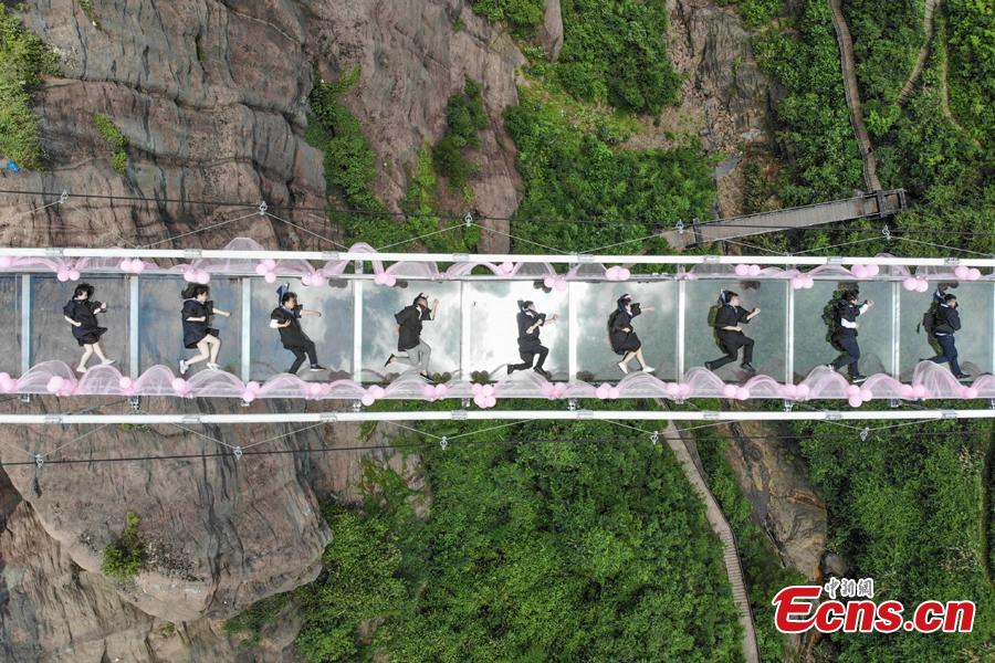 Students take creative graduation photos on a glass-bottom bridge in the Shiniuzhai National Geological Park in Pingjiang County, Central China\'s Hunan Province, June 27, 2018. The transparent bridge is suspended between two cliffs, 180 meters above ground. (Photo: China News Service/Yang Huafeng)