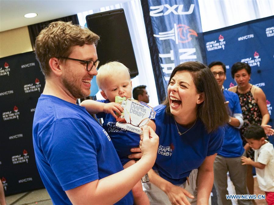 A baby winner and its parents celebrate during the Diaper Derby 2018 in New York, the United States, June 29, 2018. Diaper Derby 2018, a baby crawling contest, was held here on Friday. Around 30 babies competed to crawl across a 12-foot (3.66 meters) long mat. (Xinhua/Lin Bilin)