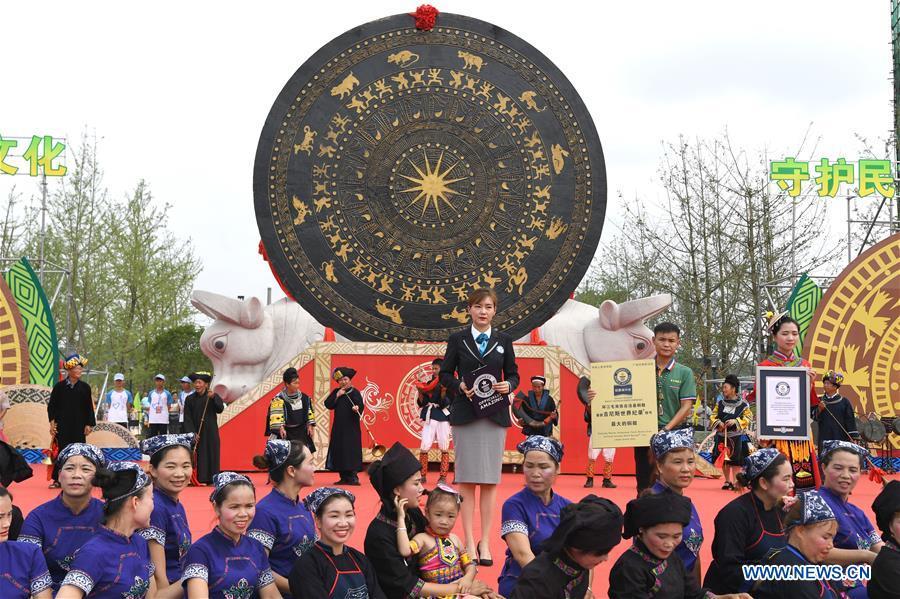 Photo taken on June 29, 2018 shows a ceremony to present the certificate for the world\'s largest bronze drum by Guinness World Records as the gigantic bronze drum (rear, C) is seen in Huanjiang Maonan Autonomous County, south China\'s Guangxi Zhuang Autonomous Region. The drum measures 6.68 meters in diameter and weighs 50 tons. It was recognized as the largest bronze drum by Guinness World Records. (Xinhua/Zhou Hua)