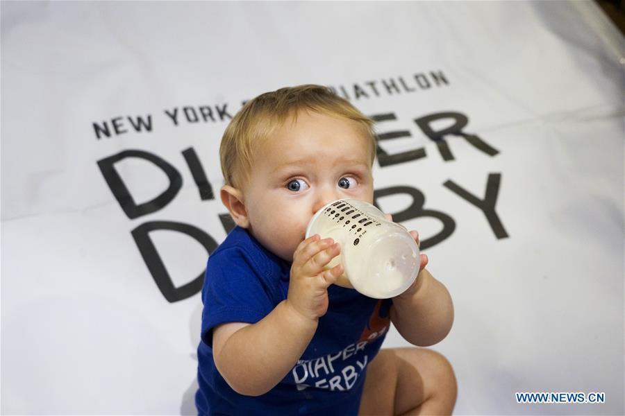 A baby drinks milk during the Diaper Derby 2018 in New York, the United States, June 29, 2018. Diaper Derby 2018, a baby crawling contest, was held here on Friday. Around 30 babies competed to crawl across a 12-foot (3.66 meters) long mat. (Xinhua/Lin Bilin)
