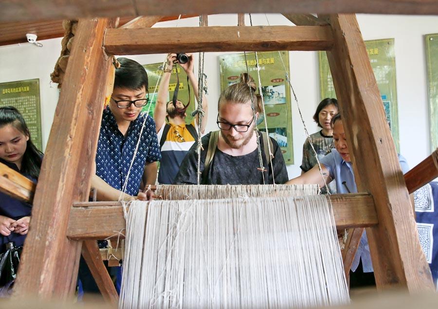 Chinese and British students from the China Academy of Art\'s creative fashion design camp experience traditional Chinese textile craft at the Blue Calico Museum in Nantong, East China\'s Jiangsu Province, on July 3, 2018. The process of making blue calico has been listed as a state-level intangible cultural heritage in China. (Photo/Asianewsphoto)
