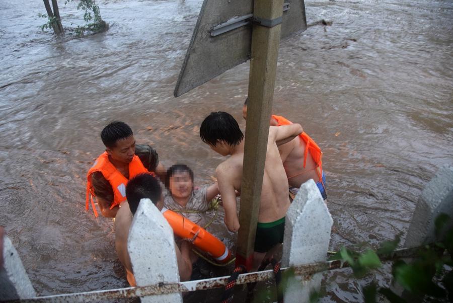A woman is rescued from flood waters and carried to safety in Huairou district, Beijing, on July 16, 2018. (Photo provided to chinadaily.com.cn)