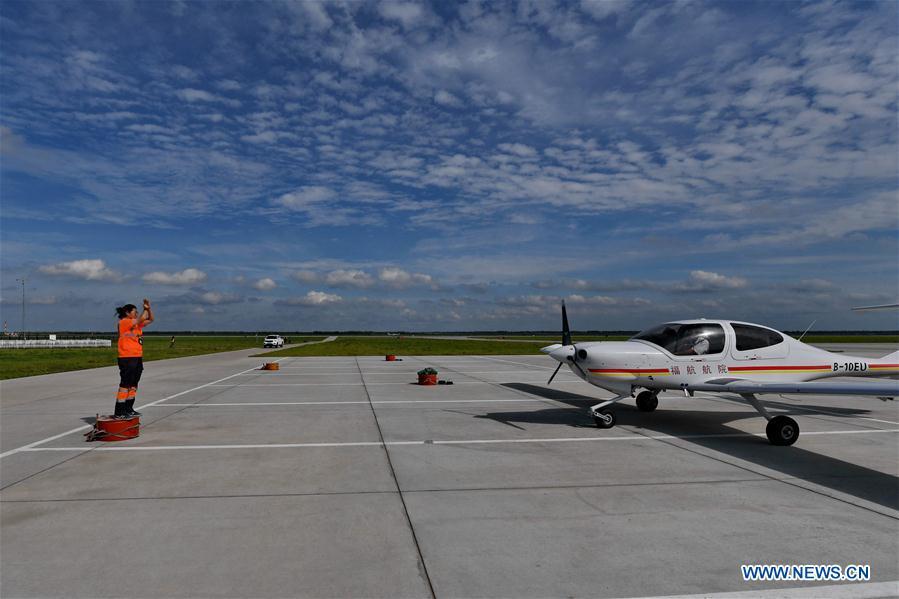 Deng Yun guides an aircraft to a specific place at the Chagan Lake airport in Songyuan, northeast China\'s Jilin Province, July 17, 2018. Deng was born in 1991. She is an aircraft maintenance technician of an aviation academy in Jilin. The young female engineer and other nine colleagues are in charge of training plane maintenance at the airport. To ensure the flight safety, they need to check more than 100 items before a plane takes off. (Xinhua/Zhang Nan)