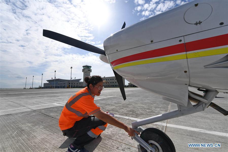 Deng Yun checks undercarriage of an aircraft at the Chagan Lake airport in Songyuan, northeast China\'s Jilin Province, July 17, 2018. Deng was born in 1991. She is an aircraft maintenance technician of an aviation academy in Jilin. The young female engineer and other nine colleagues are in charge of training plane maintenance at the airport. To ensure the flight safety, they need to check more than 100 items before a plane takes off. (Xinhua/Zhang Nan)