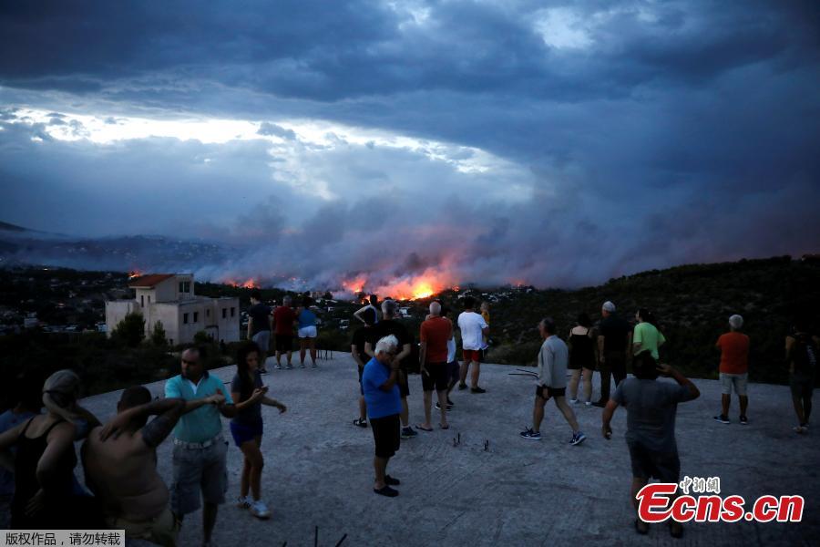 People watch a wildfire raging in the town of Rafina, near Athens, Greece, July 23, 2018. At least 20 people died and more than 100 were injured on Monday as a wildfire swept through a small resort town in eastern Greece with many victims trapped by flames as they fled. (Photo/Agencies)