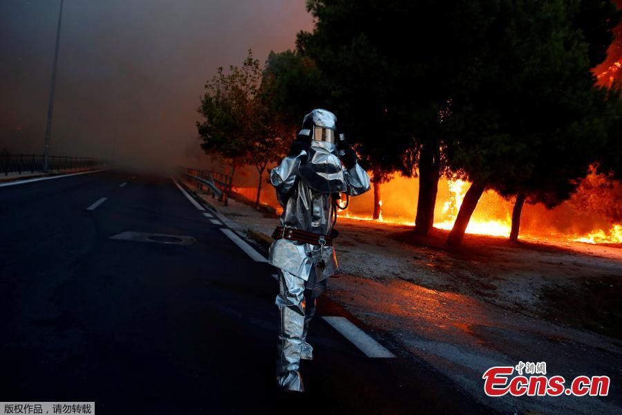 A firefighter wears a flame resistant uniform as wildfire burns in the town of Rafina, near Athens, Greece, July 23, 2018. At least 20 people died and more than 100 were injured on Monday as a wildfire swept through a small resort town in eastern Greece with many victims trapped by flames as they fled. (Photo/Agencies)