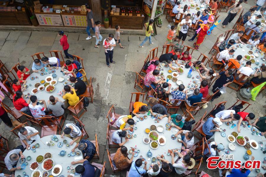 Nearly 1,000 visitors enjoy a long banquet along a street in the ancient Huangling village in Wuyuan, East China’s Jiangxi Province, Aug. 4, 2018. The connected tables stretched for hundreds of meters, and local dishes were served up for tourists. (Photo: China News Service/Fang Huabinb)