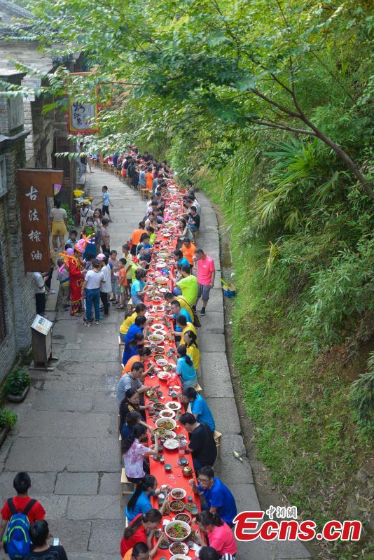 Nearly 1,000 visitors enjoy a long banquet along a street in the ancient Huangling village in Wuyuan, East China’s Jiangxi Province, Aug. 4, 2018. The connected tables stretched for hundreds of meters, and local dishes were served up for tourists. (Photo: China News Service/Fang Huabinb)