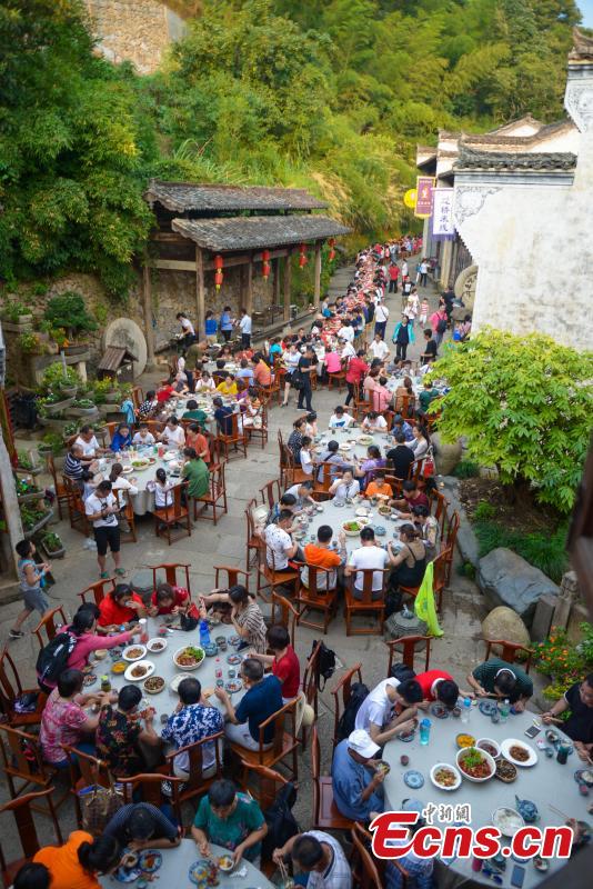 Nearly 1,000 visitors enjoy a long banquet along a street in the ancient Huangling village in Wuyuan, East China’s Jiangxi Province, Aug. 4, 2018. The connected tables stretched for hundreds of meters, and local dishes were served up for tourists. (Photo: China News Service/Fang Huabinb)