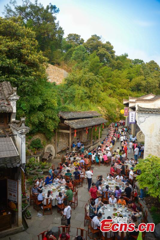 Nearly 1,000 visitors enjoy a long banquet along a street in the ancient Huangling village in Wuyuan, East China’s Jiangxi Province, Aug. 4, 2018. The connected tables stretched for hundreds of meters, and local dishes were served up for tourists. (Photo: China News Service/Fang Huabinb)