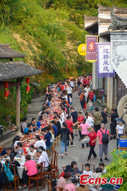 Nearly 1,000 visitors enjoy a long banquet along a street in the ancient Huangling village in Wuyuan, East China’s Jiangxi Province, Aug. 4, 2018. The connected tables stretched for hundreds of meters, and local dishes were served up for tourists. (Photo: China News Service/Fang Huabinb)