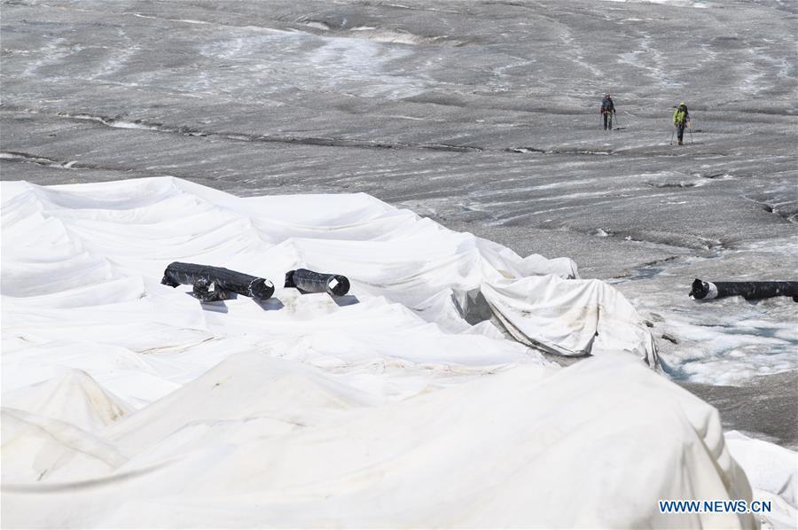 Hikers walk by the Rhone Glacier covered with white blankets near the Furka Pass in Switzerland, Aug. 5, 2018. The Rhone Glacier is protected by special white blankets to prevent it from further melting as a result of global warming. (Xinhua/Xu Jinquan)