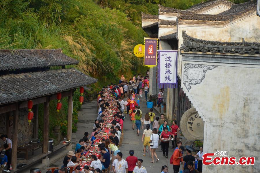 Nearly 1,000 visitors enjoy a long banquet along a street in the ancient Huangling village in Wuyuan, East China’s Jiangxi Province, Aug. 4, 2018. The connected tables stretched for hundreds of meters, and local dishes were served up for tourists. (Photo: China News Service/Fang Huabinb)