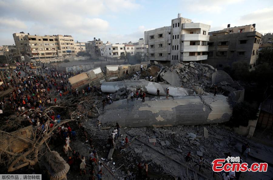 Palestinians gather around a building after it was bombed by an Israeli aircraft, in Gaza City, August 9, 2018. On Wednesday night and Thursday, Israeli aircraft struck more than 150 targets in Gaza and Palestinian militants fired scores of rockets including a long-range missile deep into Israel, escalating fighting despite the ongoing truce talks. (Photo/Agencies)