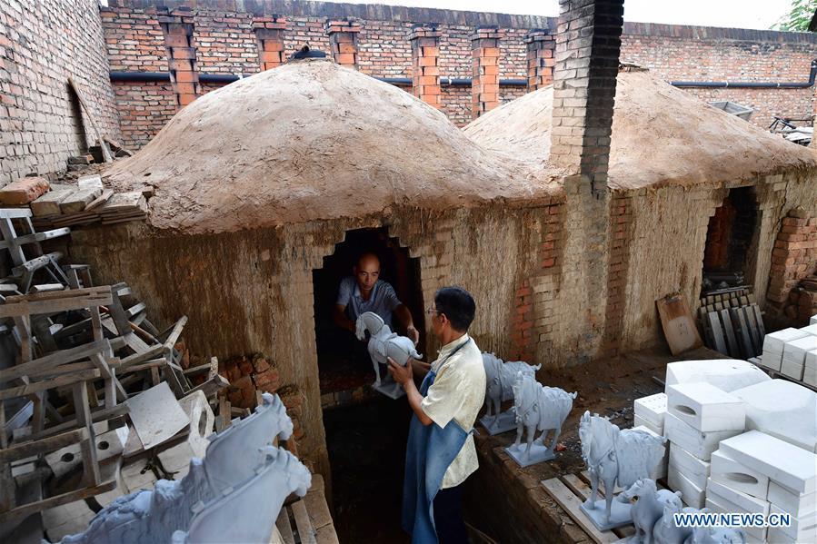 Tri-colored glazed pottery technique inheritor Gao Shuiwang (R) prepares to fire the potteries at kilns in Nanshishan Village, Mengjin County, Luoyang City, central China\'s Henan Province, Aug. 15, 2018. Gao is a leading figure in the revival of tri-colored glazed pottery, or Sancai, a Chinese porcelain characterized by a glaze with three intermingled colours. The producing technique of Sancai, which flourished in the Tang Dynasty (618-907 AD), was very complex and listed as one of China\'s National Intangible Heritages in 2008. Nanshishan Village in Henan is regarded as an important village of Sancai culture, with more than 70 enterprises now engaging in the industry. (Xinhua/Feng Dapeng)