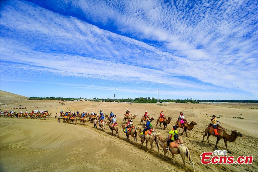 Tourists visit the Mingsha Hill scenic spot in the Gobi desert in Dunhuang City, Northwest China\'s Gansu Province, Aug. 15, 2018. Consisting of a group of sand dunes, the Mingsha Hill, or \