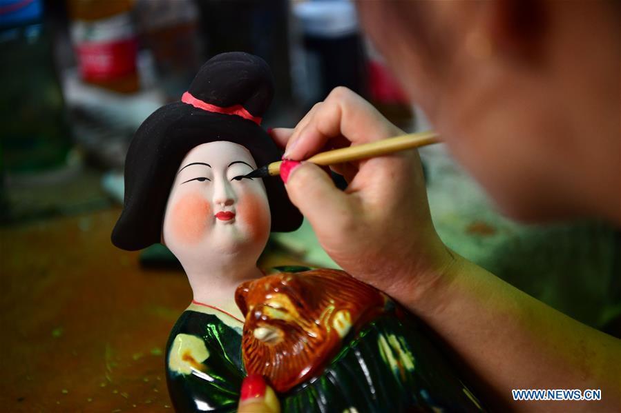 An artisan works at a workshop of Gao Shuiwang, a tri-colored glazed pottery technique inheritor, in Nanshishan Village, Mengjin County, Luoyang City, central China\'s Henan Province, Aug. 15, 2018. Gao is a leading figure in the revival of tri-colored glazed pottery, or Sancai, a Chinese porcelain characterized by a glaze with three intermingled colours. The producing technique of Sancai, which flourished in the Tang Dynasty (618-907 AD), was very complex and listed as one of China\'s National Intangible Heritages in 2008. Nanshishan Village in Henan is regarded as an important village of Sancai culture, with more than 70 enterprises now engaging in the industry. (Xinhua/Feng Dapeng)