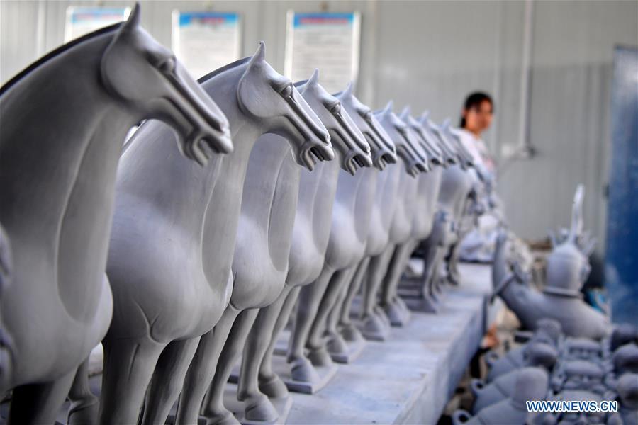 A visitor views the semi-finished potteries at a workshop of Gao Shuiwang, a tri-colored glazed pottery technique inheritor, in Nanshishan Village, Mengjin County, Luoyang City, central China\'s Henan Province, Aug. 15, 2018. Gao is a leading figure in the revival of tri-colored glazed pottery, or Sancai, a Chinese porcelain characterized by a glaze with three intermingled colours. The producing technique of Sancai, which flourished in the Tang Dynasty (618-907 AD), was very complex and listed as one of China\'s National Intangible Heritages in 2008. Nanshishan Village in Henan is regarded as an important village of Sancai culture, with more than 70 enterprises now engaging in the industry. (Xinhua/Feng Dapeng)