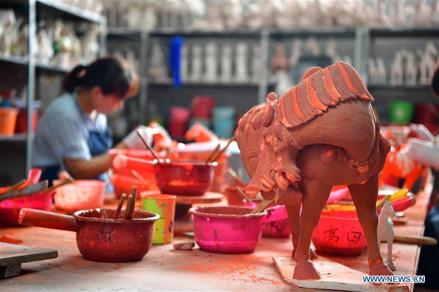 An artisan works at a workshop of Gao Shuiwang, a tri-colored glazed pottery technique inheritor, in Nanshishan Village, Mengjin County, Luoyang City, central China\'s Henan Province, Aug. 15, 2018. Gao is a leading figure in the revival of tri-colored glazed pottery, or Sancai, a Chinese porcelain characterized by a glaze with three intermingled colours. The producing technique of Sancai, which flourished in the Tang Dynasty (618-907 AD), was very complex and listed as one of China\'s National Intangible Heritages in 2008. Nanshishan Village in Henan is regarded as an important village of Sancai culture, with more than 70 enterprises now engaging in the industry. (Xinhua/Feng Dapeng)