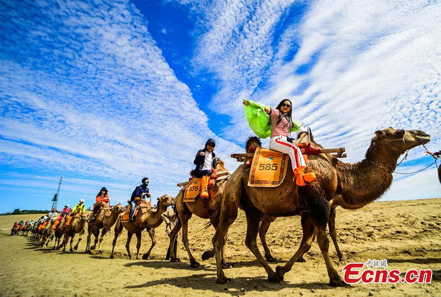 Tourists visit the Mingsha Hill scenic spot in the Gobi desert in Dunhuang City, Northwest China\'s Gansu Province, Aug. 15, 2018. Consisting of a group of sand dunes, the Mingsha Hill, or \