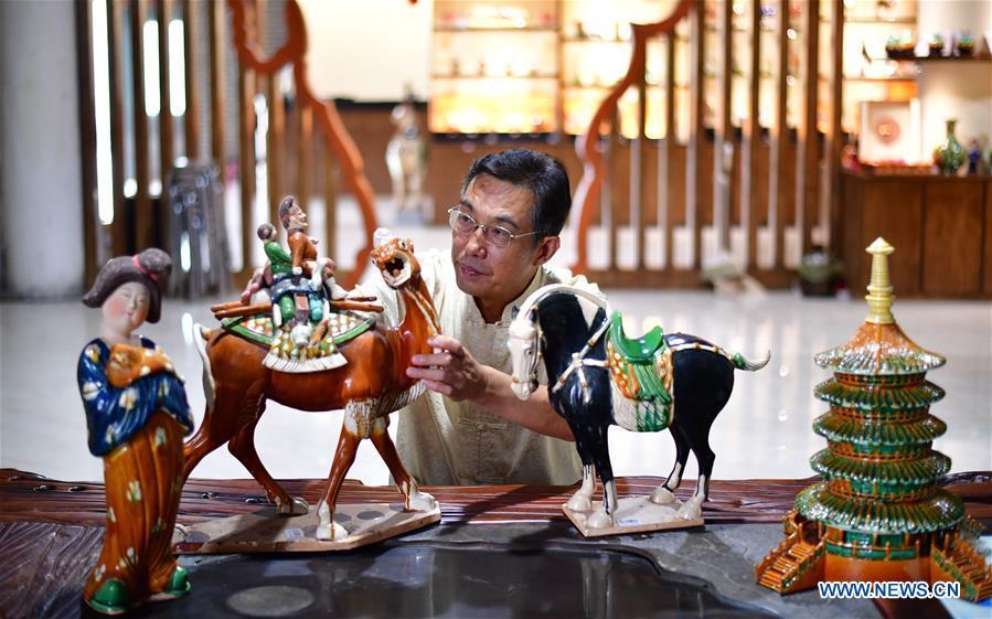 Tri-colored glazed pottery technique inheritor Gao Shuiwang checks horse potteries in Nanshishan Village, Mengjin County, Luoyang City, central China\'s Henan Province, Aug. 15, 2018. Gao is a leading figure in the revival of tri-colored glazed pottery, or Sancai, a Chinese porcelain characterized by a glaze with three intermingled colours. The producing technique of Sancai, which flourished in the Tang Dynasty (618-907 AD), was very complex and listed as one of China\'s National Intangible Heritages in 2008. Nanshishan Village in Henan is regarded as an important village of Sancai culture, with more than 70 enterprises now engaging in the industry. (Xinhua/Feng Dapeng)