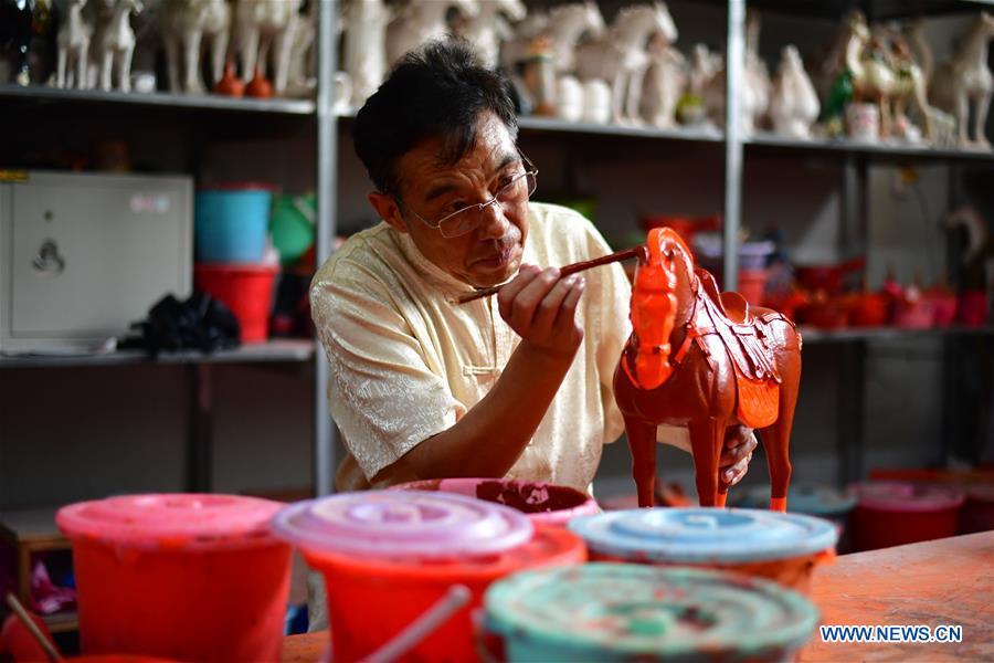 Tri-colored glazed pottery technique inheritor Gao Shuiwang makes a horse pottery in Nanshishan Village, Mengjin County, Luoyang City, central China\'s Henan Province, Aug. 15, 2018. Gao is a leading figure in the revival of tri-colored glazed pottery, or Sancai, a Chinese porcelain characterized by a glaze with three intermingled colours. The producing technique of Sancai, which flourished in the Tang Dynasty (618-907 AD), was very complex and listed as one of China\'s National Intangible Heritages in 2008. Nanshishan Village in Henan is regarded as an important village of Sancai culture, with more than 70 enterprises now engaging in the industry. (Xinhua/Feng Dapeng)