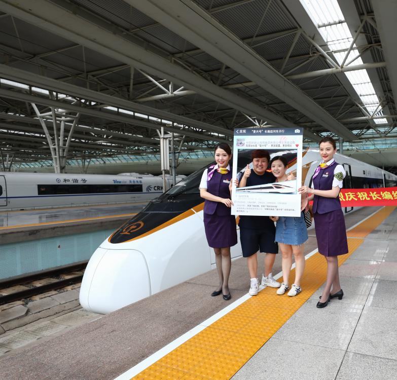 Present: Attendants of the Fuxing bullet train take photos with passengers before operation between Shanghai and Beijing. The speediest trip now takes four hours and 18 minutes. (Photo/Shine.cn)