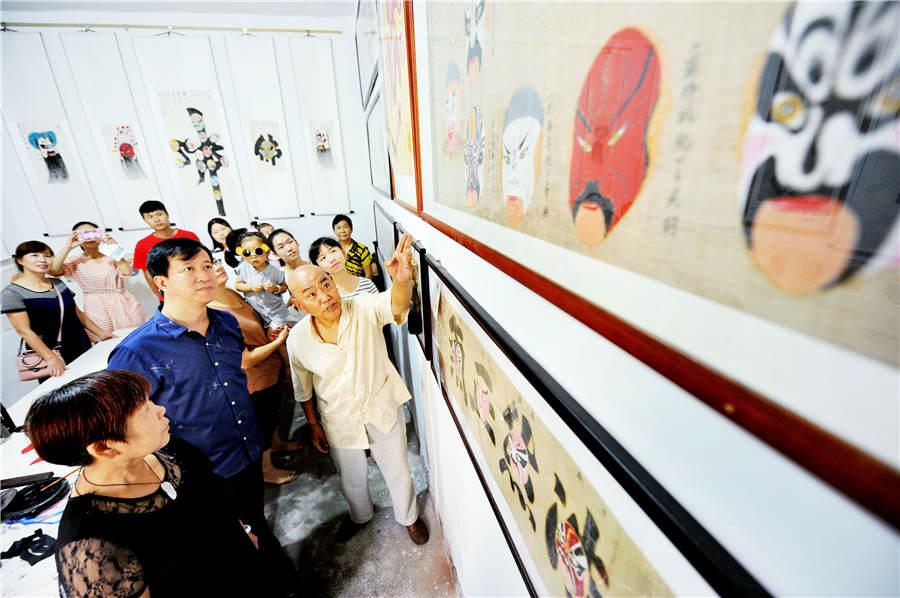 Zhao Xichun introduces his Peking Opera mask scroll in his workshop in Shaorao city, Jiangxi Province on Sept. 2, 2018.  (Photo/Asianewsphoto)