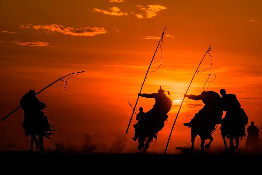 Autumn brings beautiful sunsets over open grasslands at Xilin Gol league in the Inner Mongolia autonomous region. Bathing in the sunset glow, working horses and herdsmen create a picturesque setting. (Photo/China Daily)