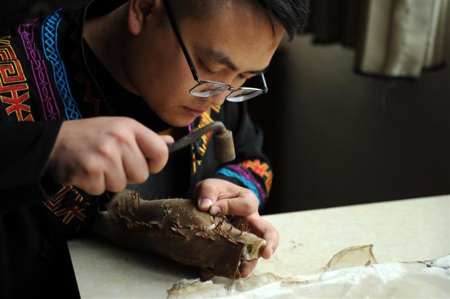 With patience and painstaking care, Gao begins work on a new piece of lacquerware. Each item needs to go through some 50 processes. (Photo/Xinhua)
Each piece of lacquerware needs to go through some 50 processes and 80 decorative finishes, such as engraving and gilding, and laying on lacquer of a different color.
Lacquerware is often molded on a base of horse or buffalo hide, shaped after being soaked in water before being dried over a fire. The process is not only time-consuming but requires great skill. Only masters with years of experience are up to the task.
Dafang County may be home to one of China’s five most highly regarded styles of lacquer, but there has been a drop in output in recent years.
“Lack of funds and a resultant decline in profit are the major reasons,” says Zhang Yu, of the county bureau of industrial economy and energy.
“But the sophisticated craftsmanship involved in making Dafang lacquerware is incomparable.”