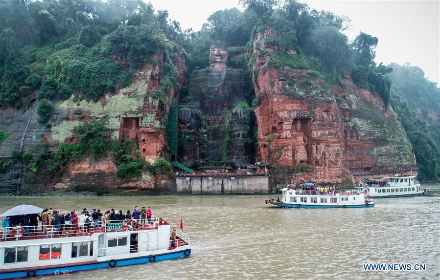 Tourists view the Leshan Giant Buddha on boat in Leshan City, southwest China\'s Sichuan Province, Oct. 19, 2018. The examination of Leshan Giant Buddha started on Oct. 8 to collect data for better restoration. (Xinhua/Chen Minxiang)