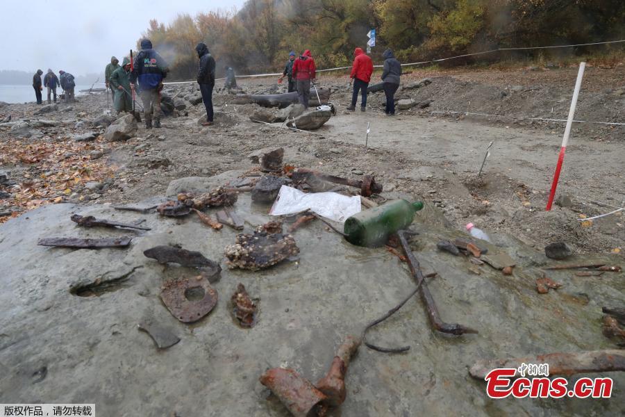 Hungarian archaeologists inspect the site where they found coins from the 16th-17th centuries and special weapons on the banks of the Danube river due to its low water level on October 25, 2018 near Erd, located 25 kilometers from Budapest. According to archaeologists working on site, the treasure comes from a cargo of a commercial ship that probably sank in the 18th century. (Photo/Agencies)