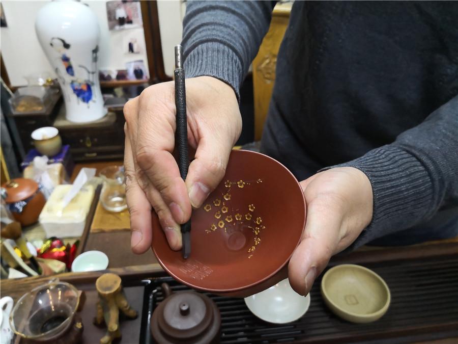 Zhao Qiushi creates the artworks of microscopic carving on a dark-red enameled pottery conditioner.  (Photo/chinadaily.com.cn)