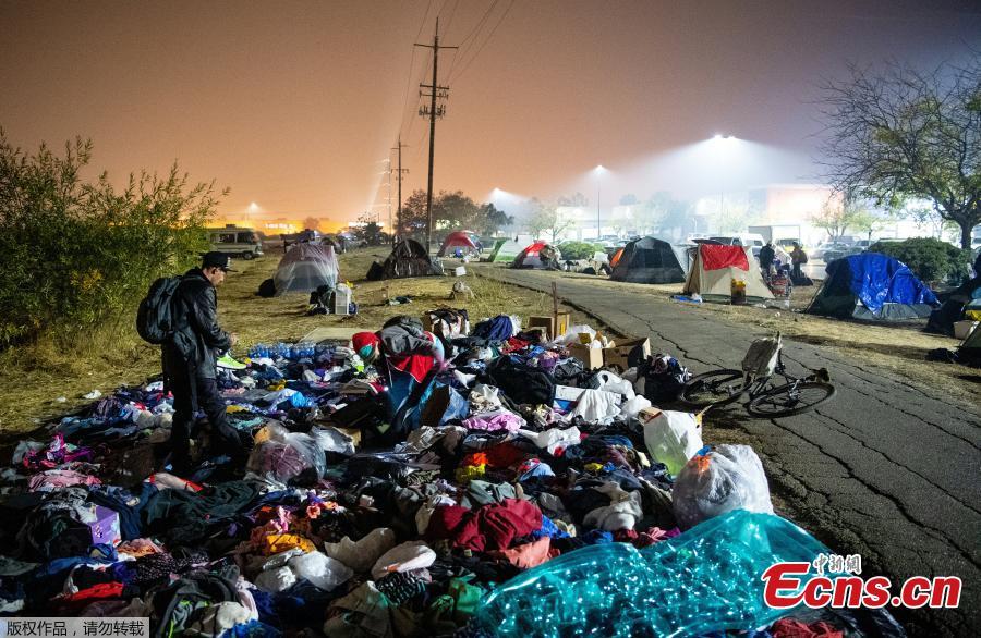 Evacuees sift through a pile of clothing at an evacuee encampment in a Walmart parking lot in Chico, California on November 17, 2018. More than 1,000 people remain listed as missing in the worst-ever wildfire to hit the US state. (Photo/Agencies)