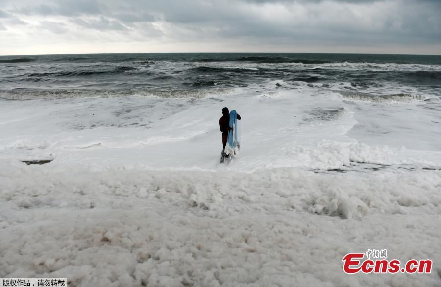 An Indian fisherman pulls in his fishing net as foamy discharge, caused by pollutants, mix with surf at a beach in Chennai on November 22, 2018. High levels of sewage and industrial waste was claimed to be the cause of the foam, officials said. (Photo/Agencies)