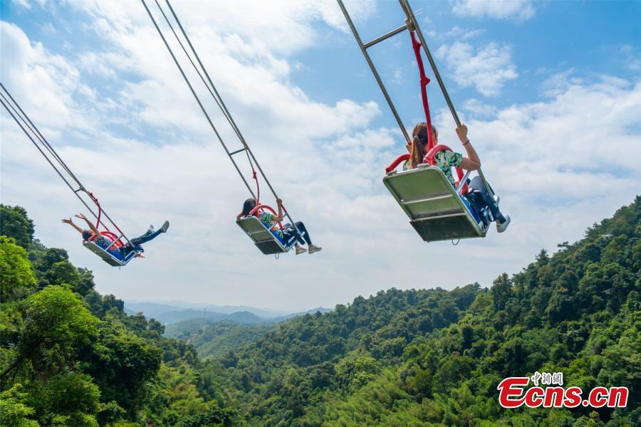 Photo shows three people up in the sky in the chair of a cliff swing that opened to the public in Qingyuan, Guangdong Province on December 19, 2018. The swing above a 198-meter waterfall on Mount Tianzi in Qingyuan, South China\'s Guangdong Province officially opens on Thursday after a four-month trial operation. (Photo: China News Service/Cheng Jingwei)