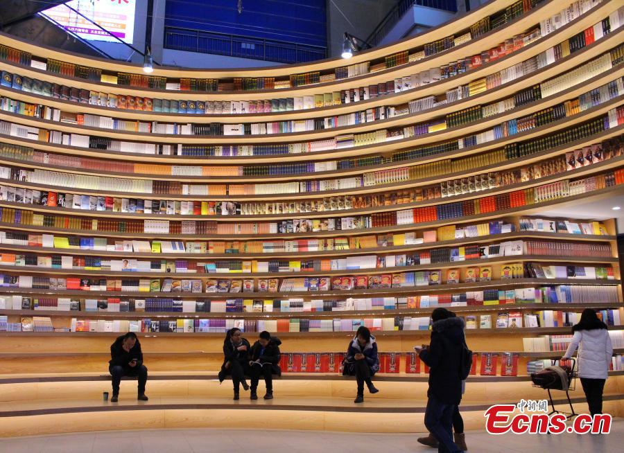 A circular wall stacked with books at a new bookstore in Hohhot, North China\'s Inner Mongolia Autonomous Region, Jan. 20, 2019. The innovative wraparound shelving units have attracted the interest of many visitors. (Photo: China News Service/Chen Feng)